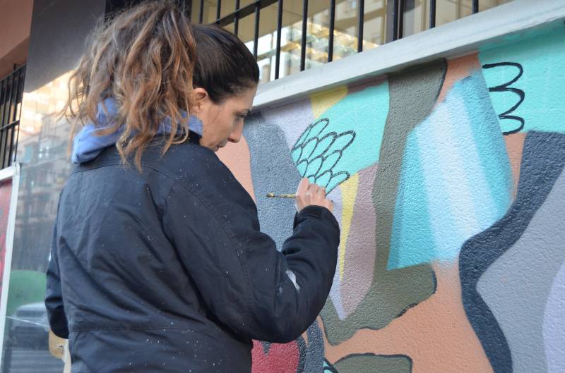 Una de las grafiteras pintando la fachada de Lambda
