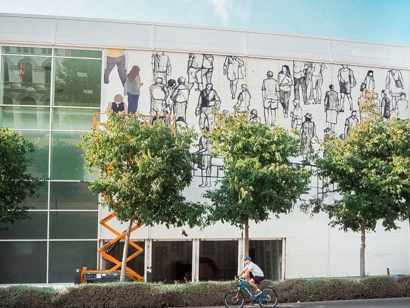 Fotografía de la intervención en fachada de La Base de la artista Hyuro, en pleno proceso.

